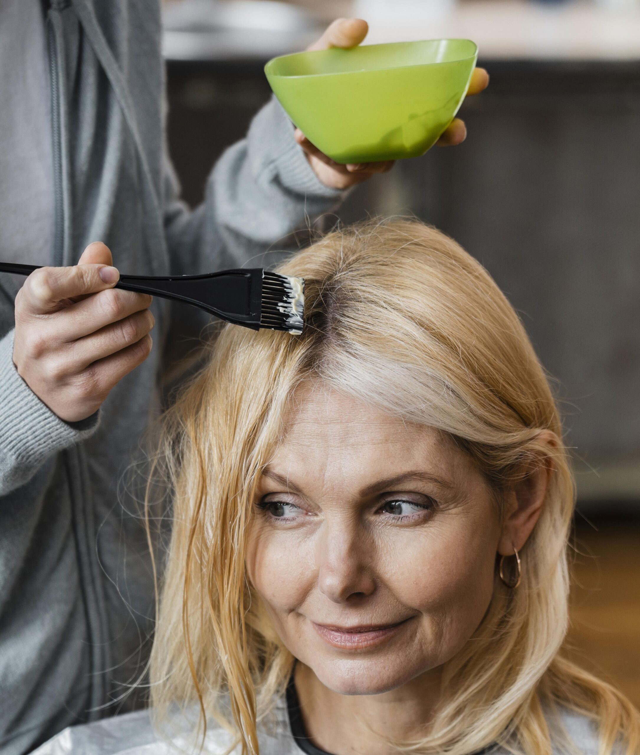 elder woman getting her hair dyed by hairdresser home